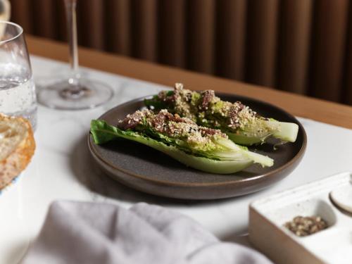 two pieces of broccoli on a plate on a table at The Porter House Hotel Sydney - MGallery in Sydney