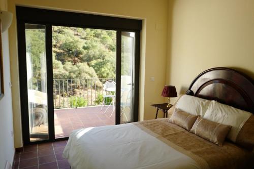 1 dormitorio con 1 cama y puerta corredera de cristal en Casa Antonio, en Alájar