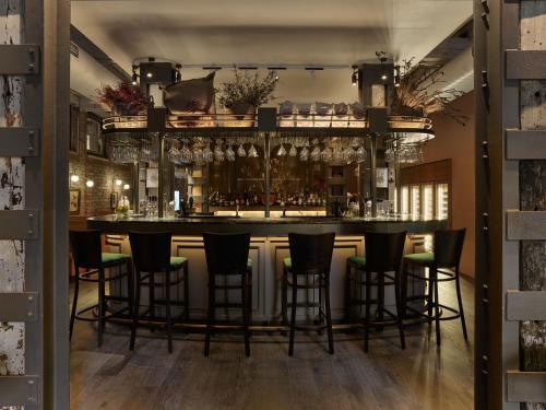 a bar with black bar stools in a room at The Porter House Hotel Sydney - MGallery in Sydney