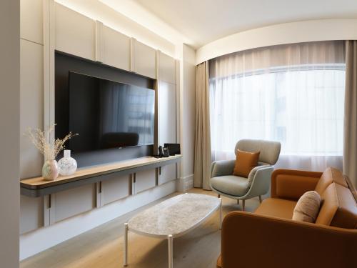 ein Wohnzimmer mit einem TV und 2 Stühlen in der Unterkunft The Porter House Hotel Sydney - MGallery in Sydney