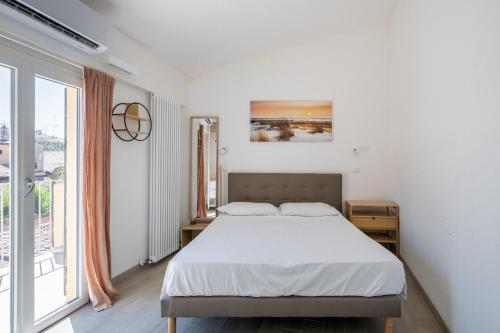 a white bedroom with a bed and a large window at Appartamento vicino all'Orto Botanico by Wonderful Italy in Bologna