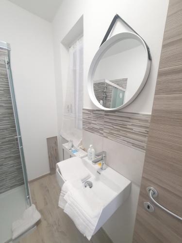 Baño blanco con lavabo y espejo en Mini Suite Valentino, en Casale Monferrato