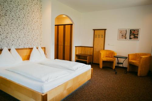 a bedroom with a large bed and a chair at Gailtaler Hof in Kötschach