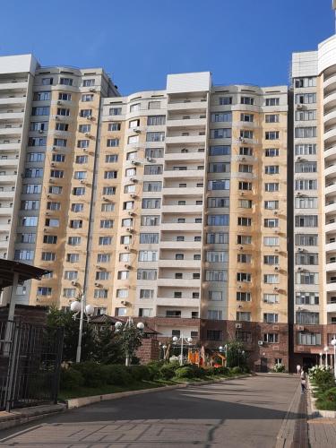 una calle vacía frente a un gran edificio de apartamentos en Просторная квартира в жк Науаи около ТРЦ МЕГА, en Almaty