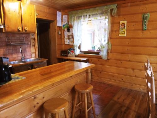 una cocina con encimera y taburetes en una cabaña en Cztery Pory Roku - Dom en Lutowiska