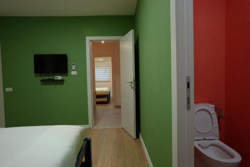 a room with green walls and a bed and a toilet at RAKEFET - Traveler's House - EILAT in Eilat