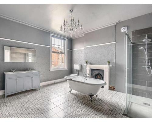 a bathroom with a bath tub and a chandelier at Victoria House in Southport