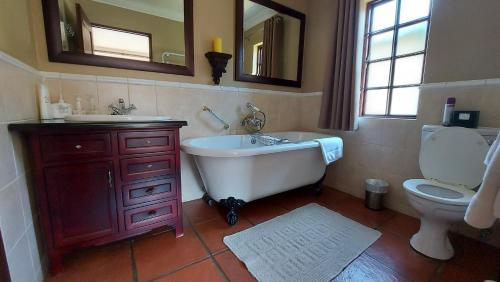 ein Badezimmer mit einer Badewanne, einem WC und einem Waschbecken in der Unterkunft Aviemore Lodge in Dullstroom