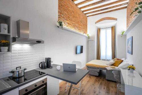 a kitchen and living room with a laptop on a table at Milano City Apartments - Duomo Brera - Elegant Suite in Design District in Milan