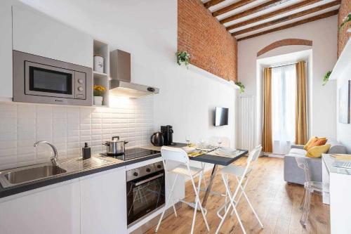 a kitchen with a sink and a table with chairs at Milano City Apartments - Duomo Brera - Elegant Suite in Design District in Milan
