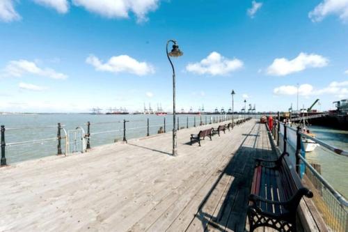 a wooden pier with benches on the water at Sea Breeze is next to the Beach & Harbour in Harwich