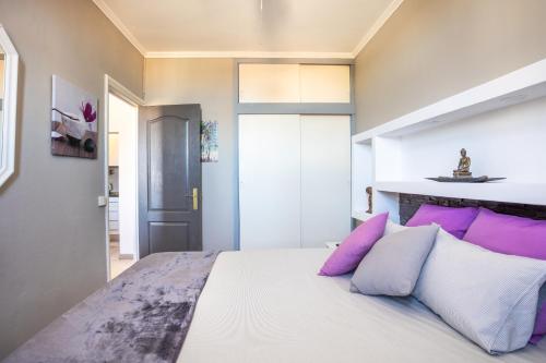 Schlafzimmer mit einem Bett mit lila und weißen Kissen in der Unterkunft Medano Time in El Médano