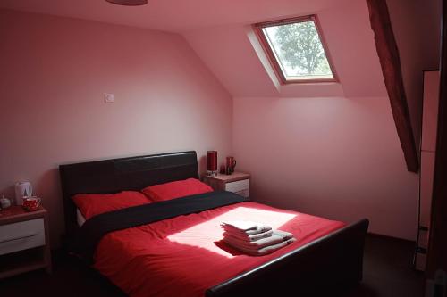 Un dormitorio con una cama roja con sábanas rojas y una ventana en Le Noble Jardin, en Mohon