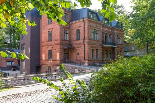 an old red brick building with trees in front of it at Vallikraavi Studio Apartment in Tartu