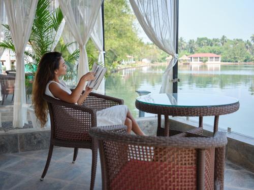 a woman sitting in a chair reading a book at Veda5 Wellness Retreat & Spa in Old Goa