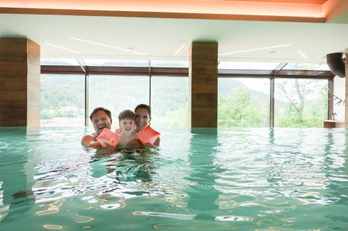 three people in the water in a swimming pool at Hotel Il Cervo, SPA & Wellness, Bike Hotel in Tarvisio