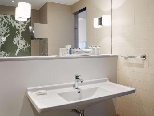 a bathroom with a white sink and a mirror at Radisson Blu Hotel, Hasselt in Hasselt