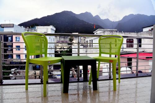 two green chairs and a table on a balcony at The Divine Oak Golden Leaf in Katra