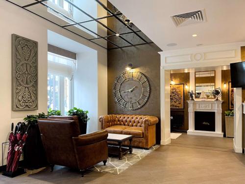 a lobby with a couch and a clock on the wall at Best Western Plus Market Square Lviv in Lviv