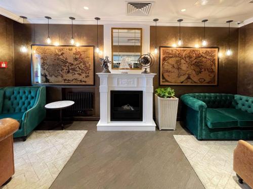 a living room with two green couches and a fireplace at Best Western Plus Market Square Lviv in Lviv