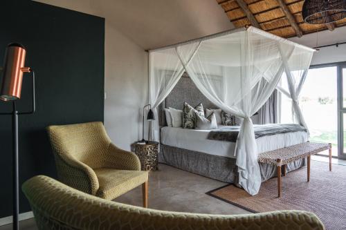um quarto com uma cama de dossel e uma cadeira em Xanatseni Private Camp em Klaserie Private Nature Reserve