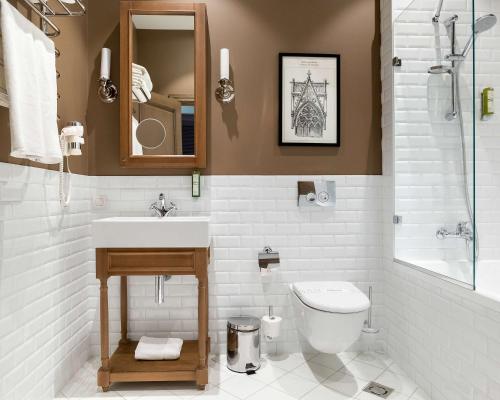 a bathroom with a sink and a toilet and a mirror at Best Western Plus Market Square Lviv in Lviv