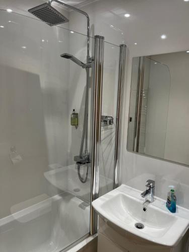 ein weißes Bad mit einer Dusche und einem Waschbecken in der Unterkunft Cumberland Hotel in Edinburgh