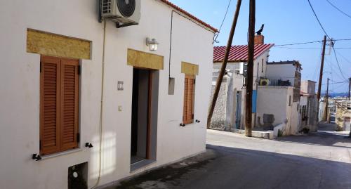 a white building with brown doors on a street at Alicia's Traditional Home In Paradisi in Paradeísion