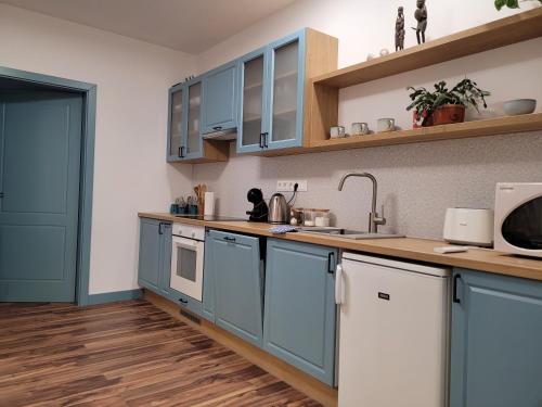 een keuken met blauwe kasten en een houten vloer bij Jégmadár Apartman in Debrecen