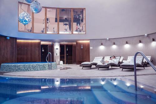 阿尼克什奇艾的住宿－阿尼克什奇艾-維爾紐斯SPA酒店，坐在游泳池旁沙发上的女人