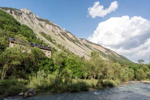 a building on the side of a mountain next to a river at Parador de Bielsa in Espierba