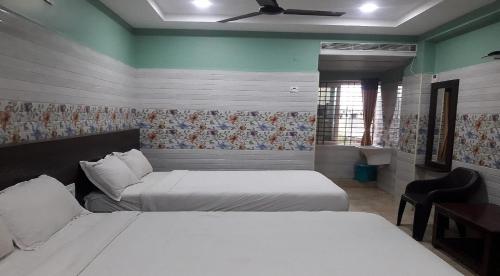 a bedroom with two beds and a ceiling fan at Surya Grand Tiruchanoor Tirupati in Tirupati