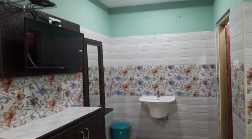 a bathroom with a sink and a tv on the wall at Surya Grand Tiruchanoor Tirupati in Tirupati