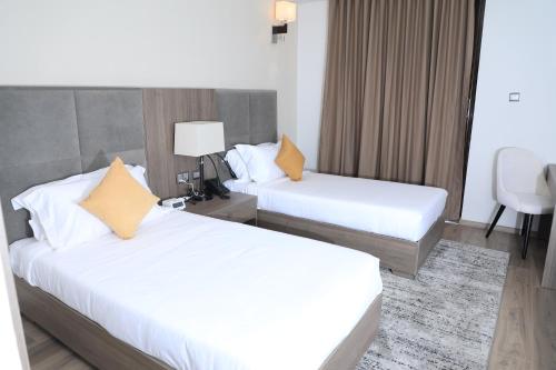 two beds in a hotel room with white sheets and yellow pillows at TH BonRoyal Hotel in Addis Ababa