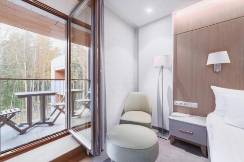 a room with a bed and a chair and a balcony at SPA VILNIUS Anykščiai in Anykščiai