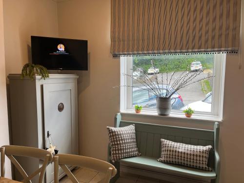 una ventana con una silla verde y una cortina en CWTCH COTTAGE Llantrisant 2 bed home - sleeps 4, en Llantrisant