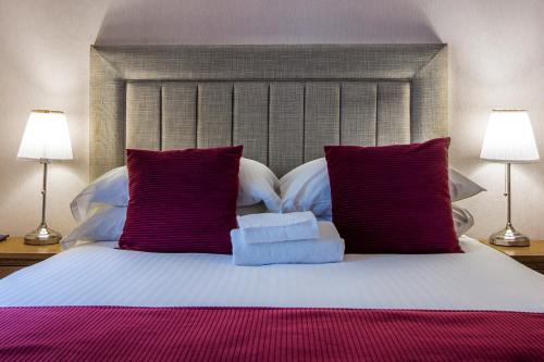 a bed with purple pillows and two towels on it at The Knight Residence by Mansley in Edinburgh