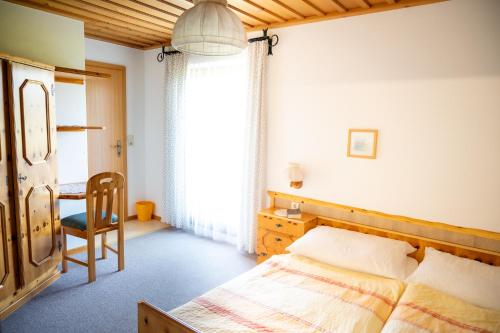 um quarto com uma cama, uma cadeira e uma mesa em Gästehaus Macheiner em Mariapfarr
