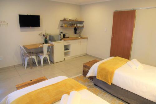 a room with two beds and a kitchen and a table at Nini's guest units in Bloemfontein