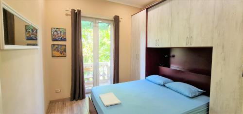 niewielka sypialnia z niebieskim łóżkiem i oknem w obiekcie 2V1 - Blloku MAC w Tiranie