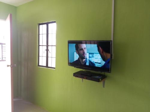 a flat screen tv on a green wall in a room at Budget Home in Iloilo Staycation At 8 Pax in Oton