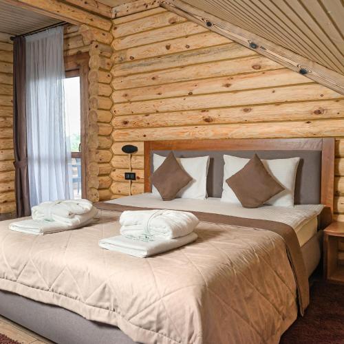 a bedroom with a large bed in a log cabin at Forest resort BalQaragai in Malotimofeyevka