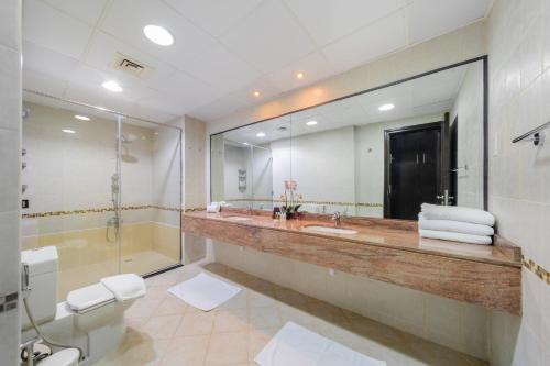 een badkamer met een wastafel, een douche en een spiegel bij EDEN'S Homes & Villas - Royal Oceanic in Dubai