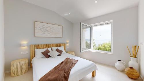 een witte slaapkamer met een bed en een raam bij Gemütliche Villa mit Pool in Brela