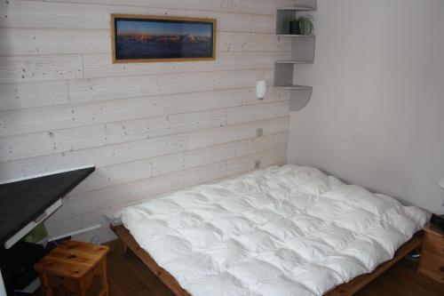 Bett in einem Zimmer mit einer weißen Wand in der Unterkunft Appartement T3 pour 6 personnes in Tignes
