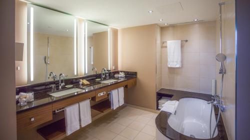 a bathroom with a tub and a sink and a toilet at Mövenpick Hotel Geneva in Geneva