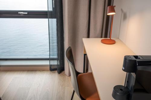 a desk with a lamp and chairs in a room with a window at Quality Hotel Harstad in Harstad