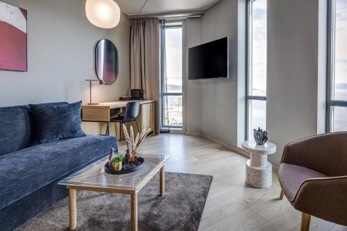 a living room with a blue couch and a table at Quality Hotel Harstad in Harstad