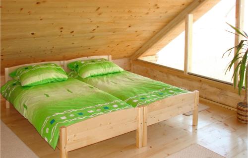 een bed met groene lakens en kussens in een houten kamer bij Amazing Home In Mscice With Wifi in Podamirowo