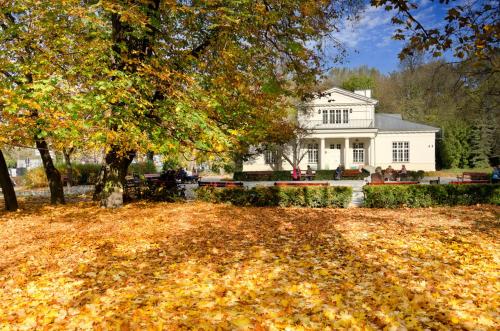 a white house with a large yard with leaves on the ground at JUNA2 - nowoczesny apartament w centrum z widokiem na park in Pruszków